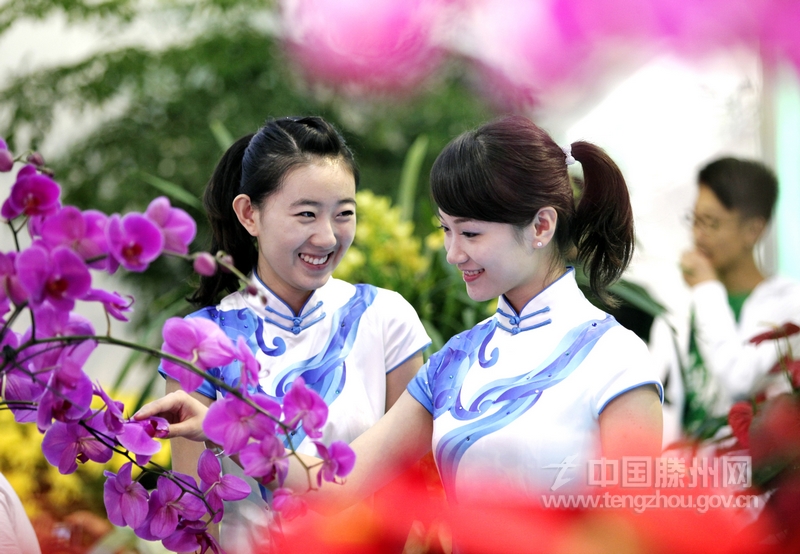 【新华社通稿图片】两名少女在第五届山东省花卉博览会展览馆内观赏花卉