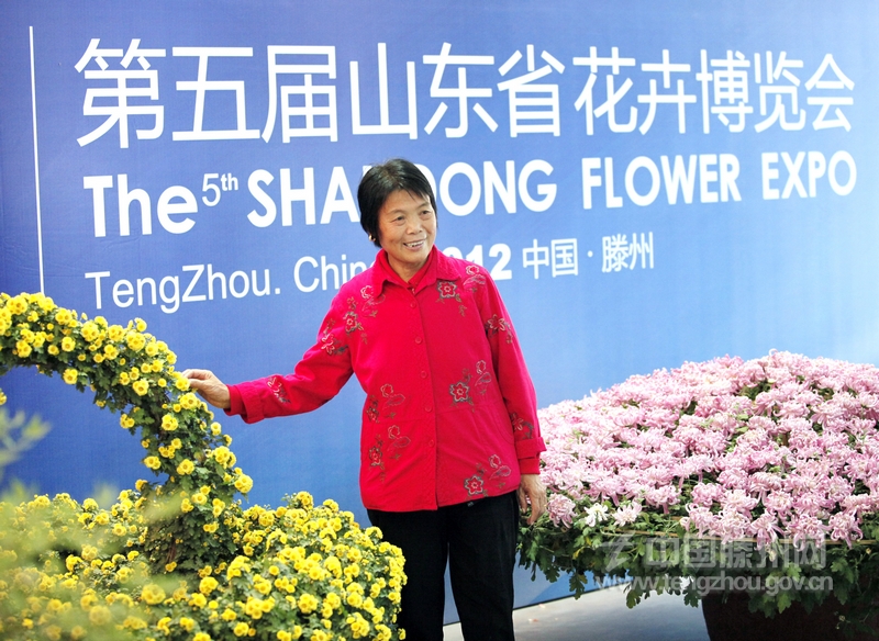 第五届山东省花卉博览会展览馆内，一位市民正在展牌前留影